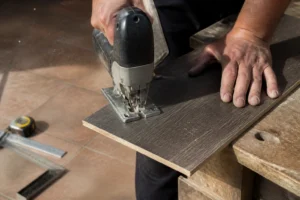 Découpe d'une lame de parquet stratifié à la scie sauteuse sur un établi de chantier en bois