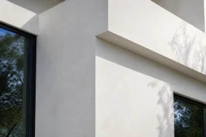Façade en béton blanc lissé d'une maison contemporaine sous lumière naturelle