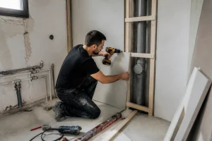 Coffrage placo sans rail réalisé avec des tasseaux en bois autour d'un tuyau dans une pièce en rénovation