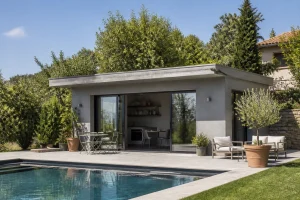 Pool house en béton avec toit plat installé au bord d'une piscine dans un jardin