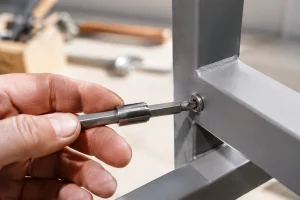 Main insérant un embout hexagonal dans une vis Allen sur une pièce métallique en atelier